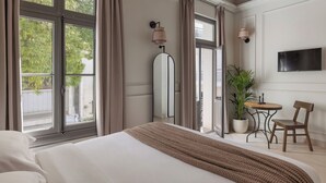 Habitación de hotel con cama, planta en maceta, televisor y una silla.