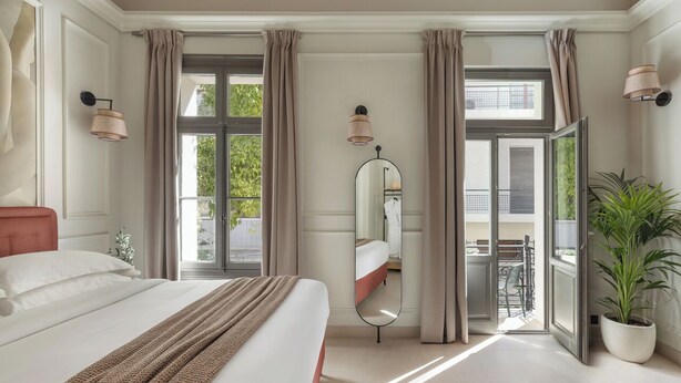 Un dormitorio con cama, un espejo grande, una planta en maceta y un balcón con vistas.