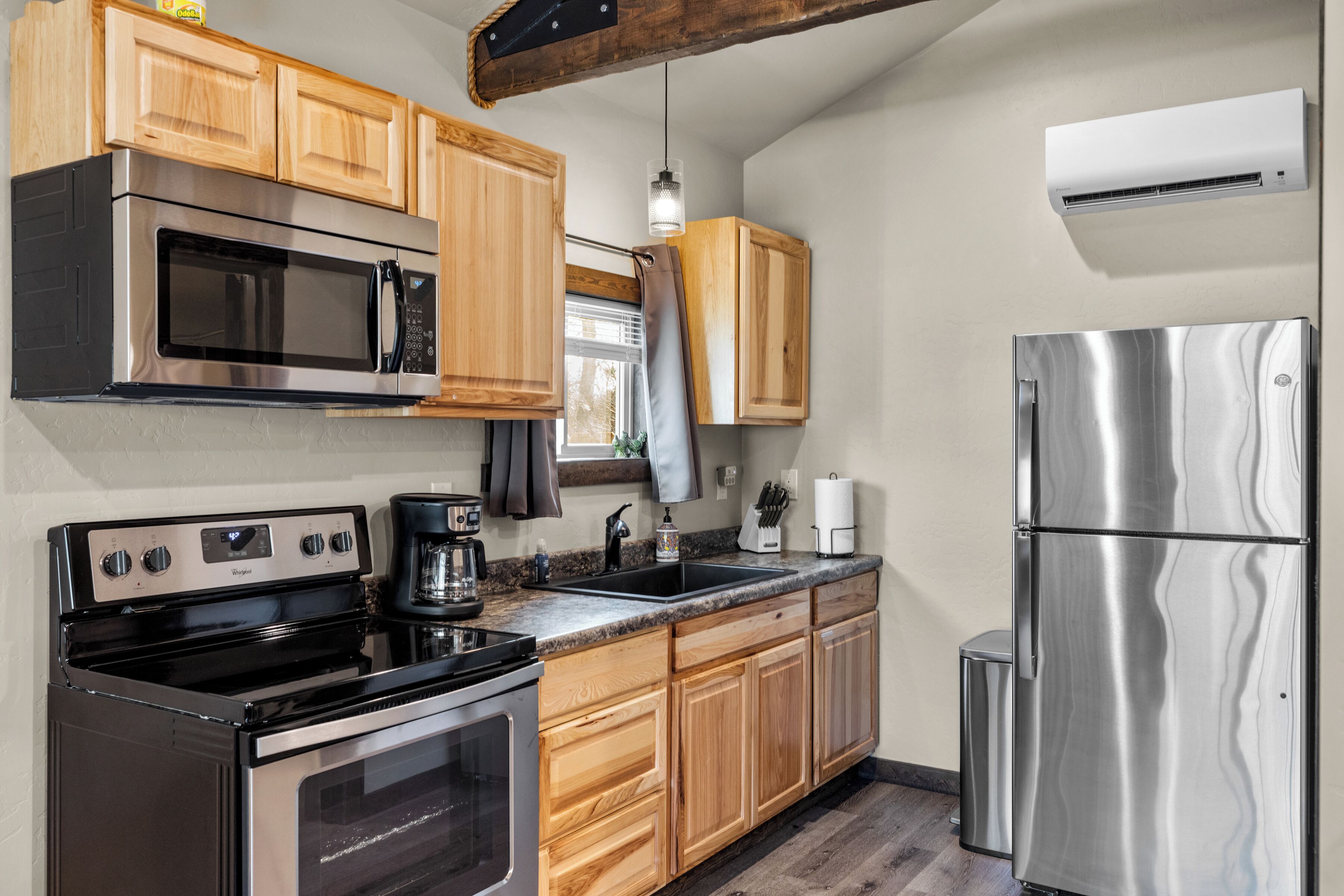 A kitchen with wooden cabinets, stainless steel appliances, and a window.