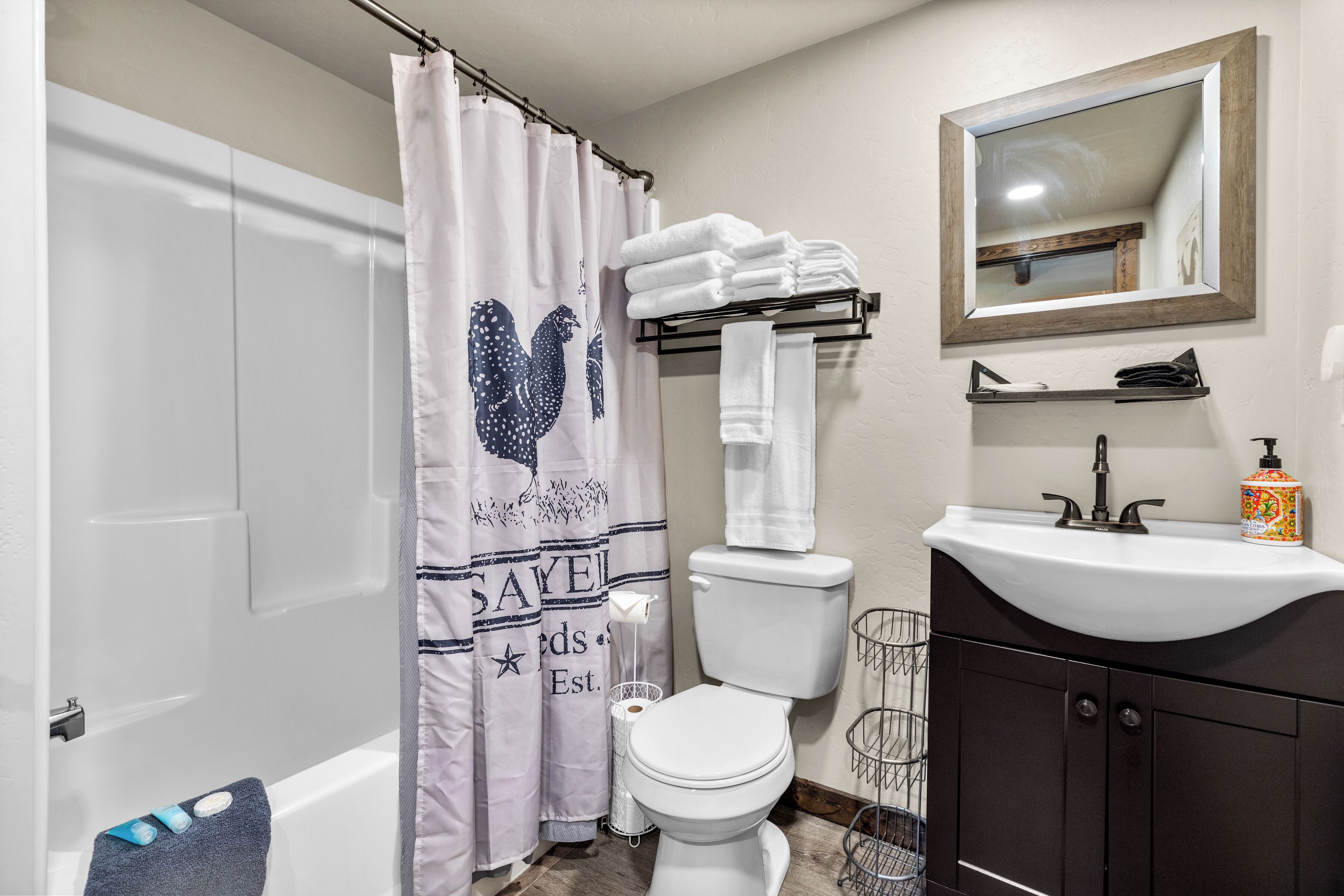 A bathroom with a shower curtain, toilet, sink, and mirror.