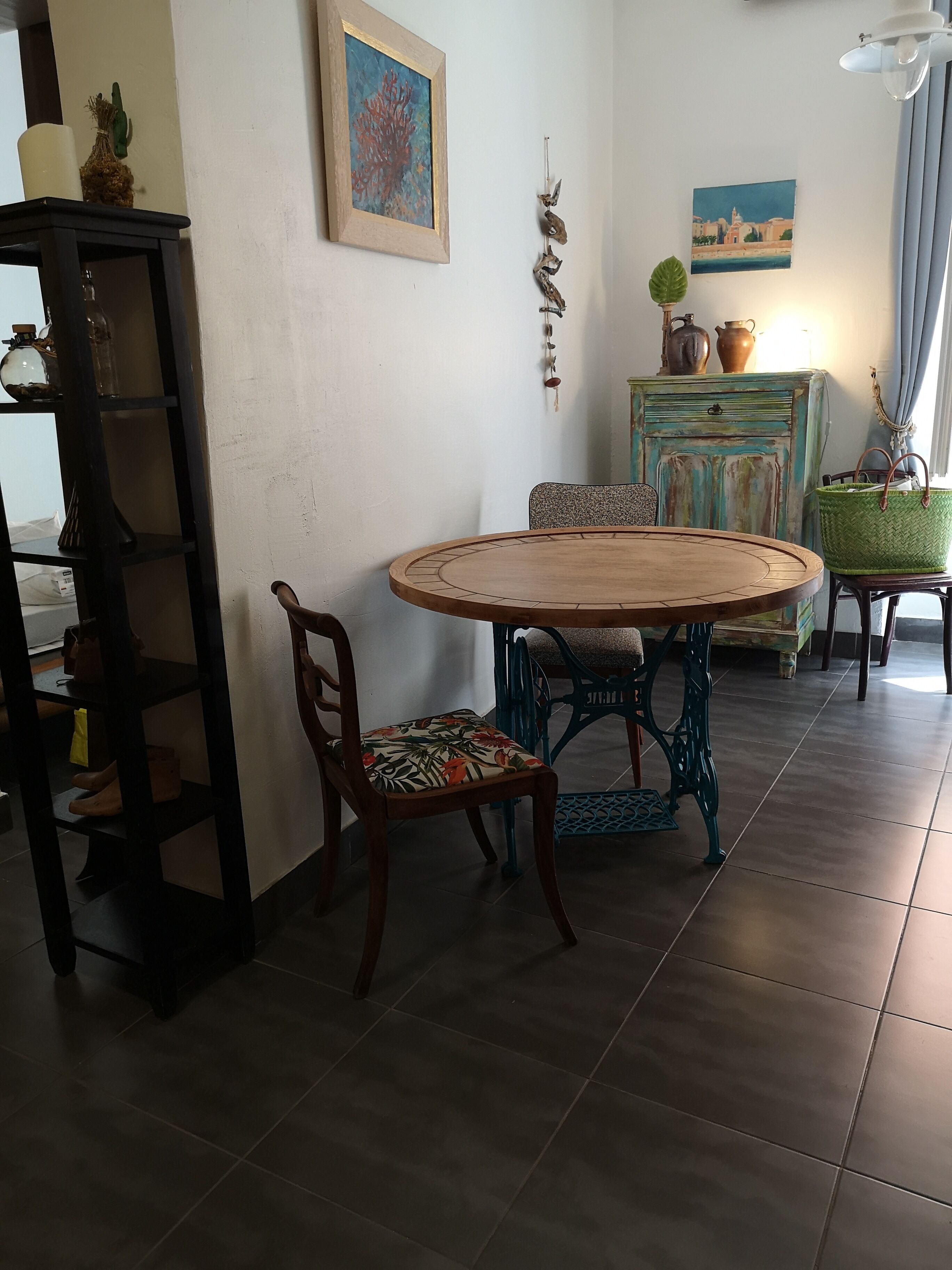 A dining area with a round wooden table, two chairs, a small cabinet, and a shelf with shoes.