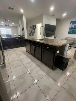 A modern kitchen with a central island, built-in appliances, and a large window.