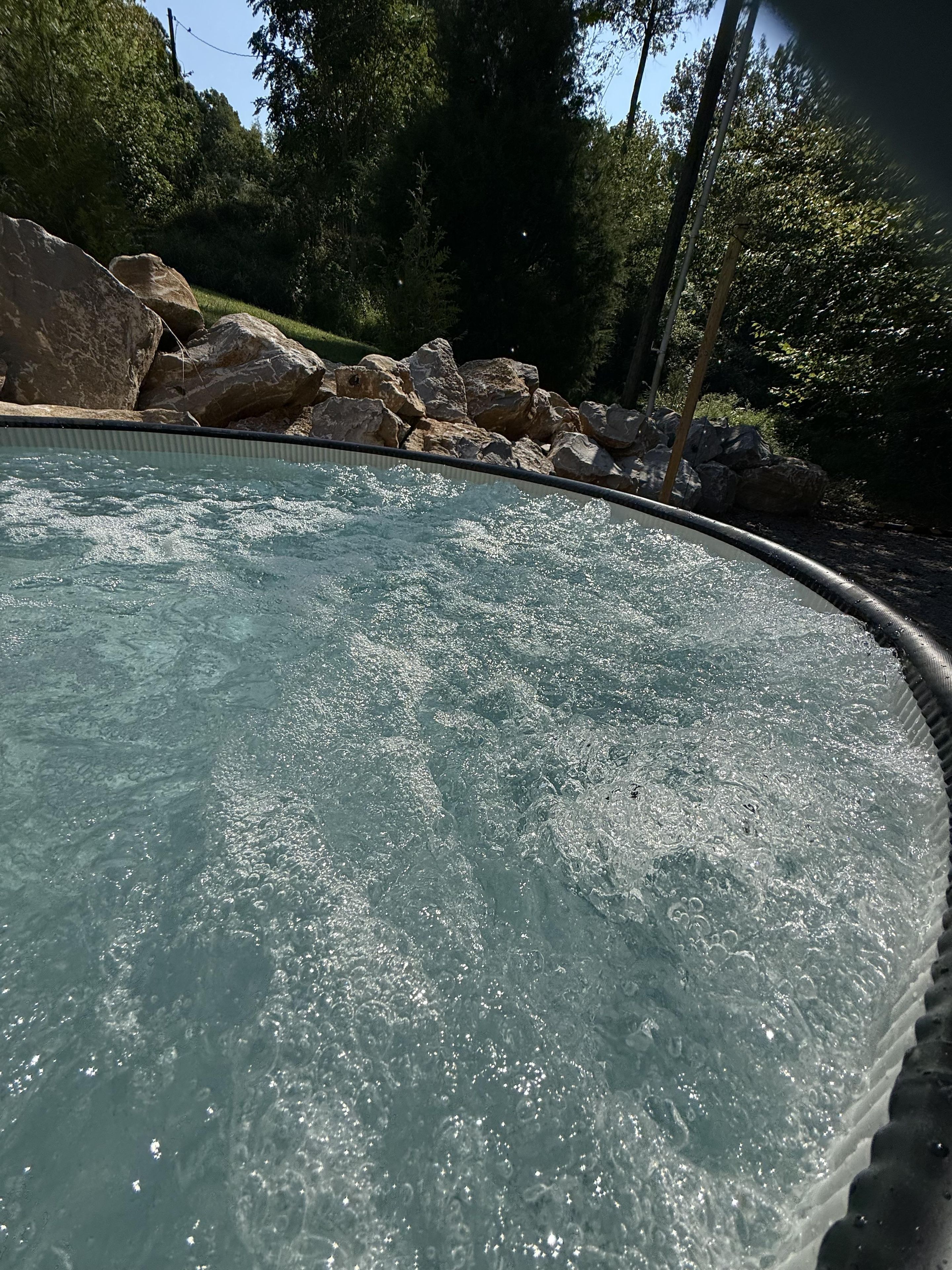 A pool with clear water, surrounded by rocks and trees.
