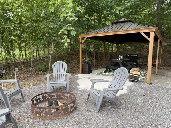 Un espacio de estar al aire libre cubierto con sillas Adirondack, una chimenea y una parrilla.
