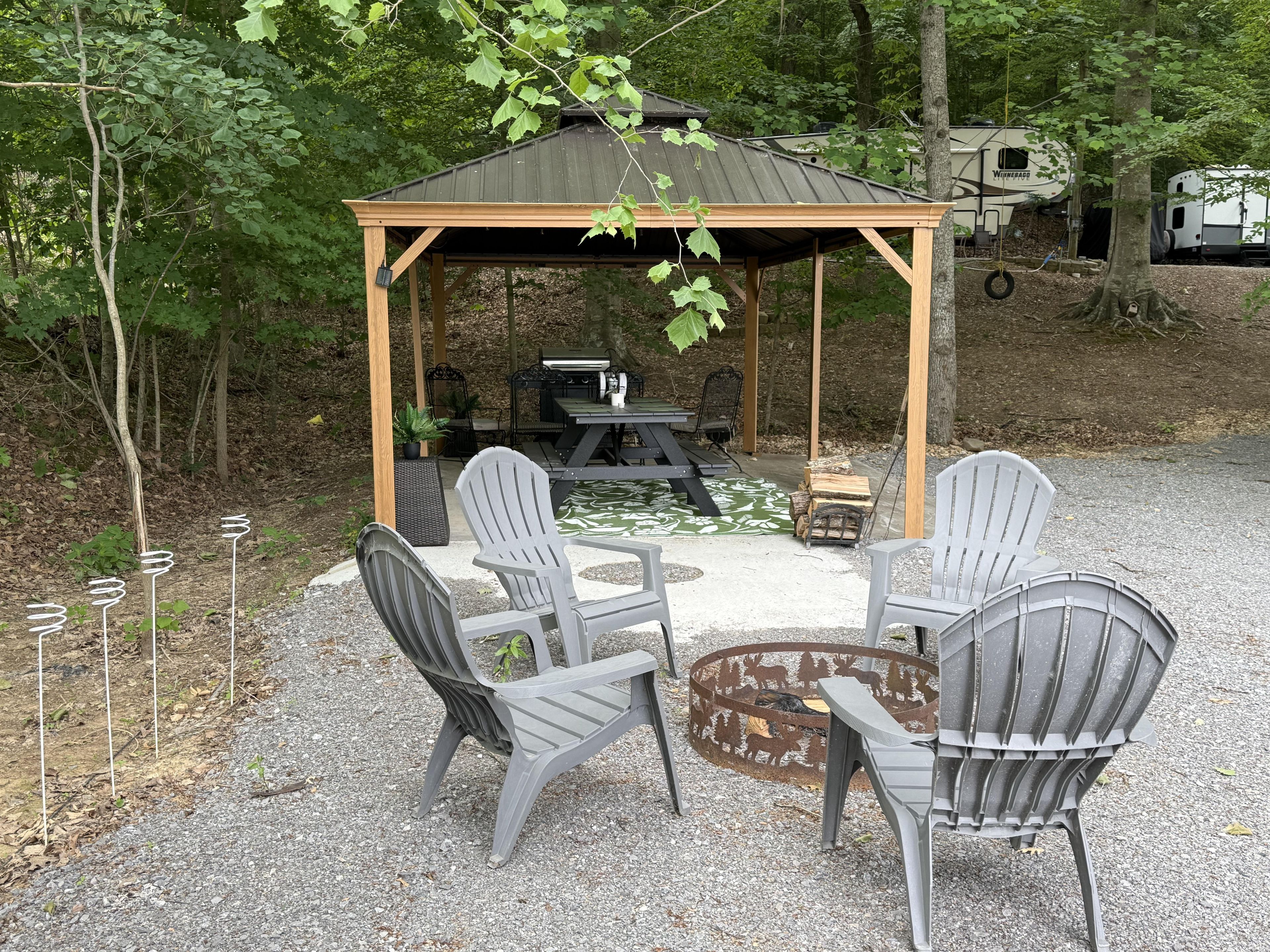 Un belvédère avec une table et des chaises, entouré d’arbres.