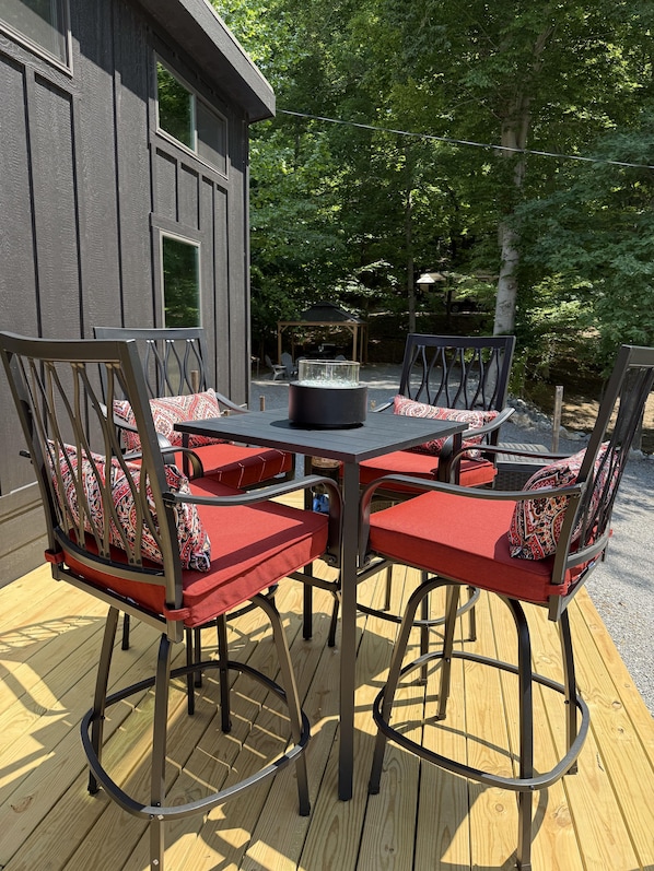 Une terrasse avec une table et des chaises, un foyer et un espace salon abrité.