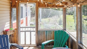 Eine Holzterrasse mit Glastür zum Patio, zwei Stühle und ein Tisch.