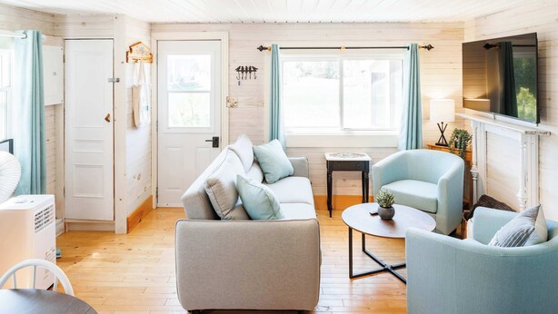 Ein gemütliches Wohnzimmer mit einer Couch, Sesseln, einem Fernseher und einem Kamin.