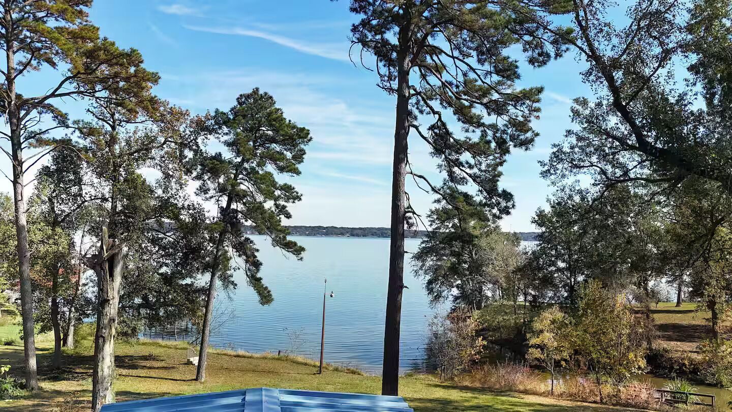 Blick auf einen See mit Bäumen und blauem Himmel.