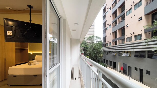 Ein modernes Hotelzimmer mit Balkon, einem Bett, einem Schreibtisch und einem großen Fenster.