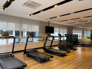 Un gimnasio con cintas de correr, elípticas y una pantalla de televisión.