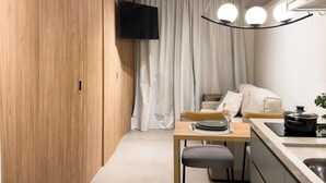 Eine moderne Küche mit Essbereich, Holzschränken, einem Flachbildfernseher und einer Pendelleuchte.