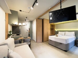 Een moderne hotelkamer met een bed, een televisie, een zithoek en een inloopkast.