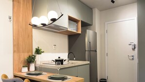 Une cuisine moderne dotée d’un îlot central intégré, d’appareils électroménagers en acier inoxydable et d’un luminaire suspendu.