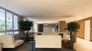 Un hall d’entrée moderne, doté de sièges, de grandes fenêtres et de plantes d’intérieur.