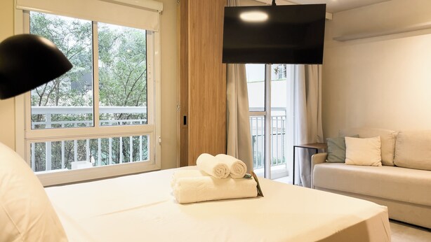 Une chambre d’hôtel avec un lit, une télévision, un balcon et un canapé.