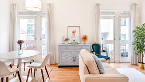 Un salon comprenant un canapé, une table à manger avec des chaises, un meuble et un fauteuil.