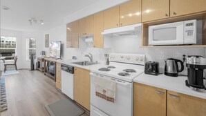 Una cocina moderna con electrodomésticos blancos, armarios de madera y un microondas en la encimera.