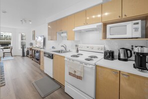 Eine moderne Küche mit weißen Geräten, Holzschränken und einer Mikrowelle auf der Arbeitsplatte.