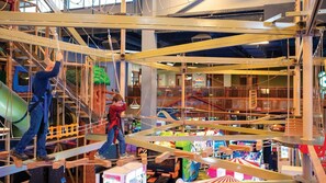 Ein Indoor-Spielbereich mit Klettergerüst und Rutsche.