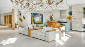 A modern hotel lobby with a sofa, wooden reception desk, and a large abstract painting. - Miami Beach Studio – Walk to South Beach & Art Deco District (Miami Beach)