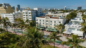 A multi-story hotel with a central courtyard, palm trees, and a view of the city skyline. - Miami Beach Studio – Walk to South Beach & Art Deco District (Miami Beach)
