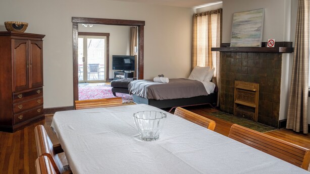 Quarto com cama, lareira, televisão e área de jantar com mesa e cadeiras.