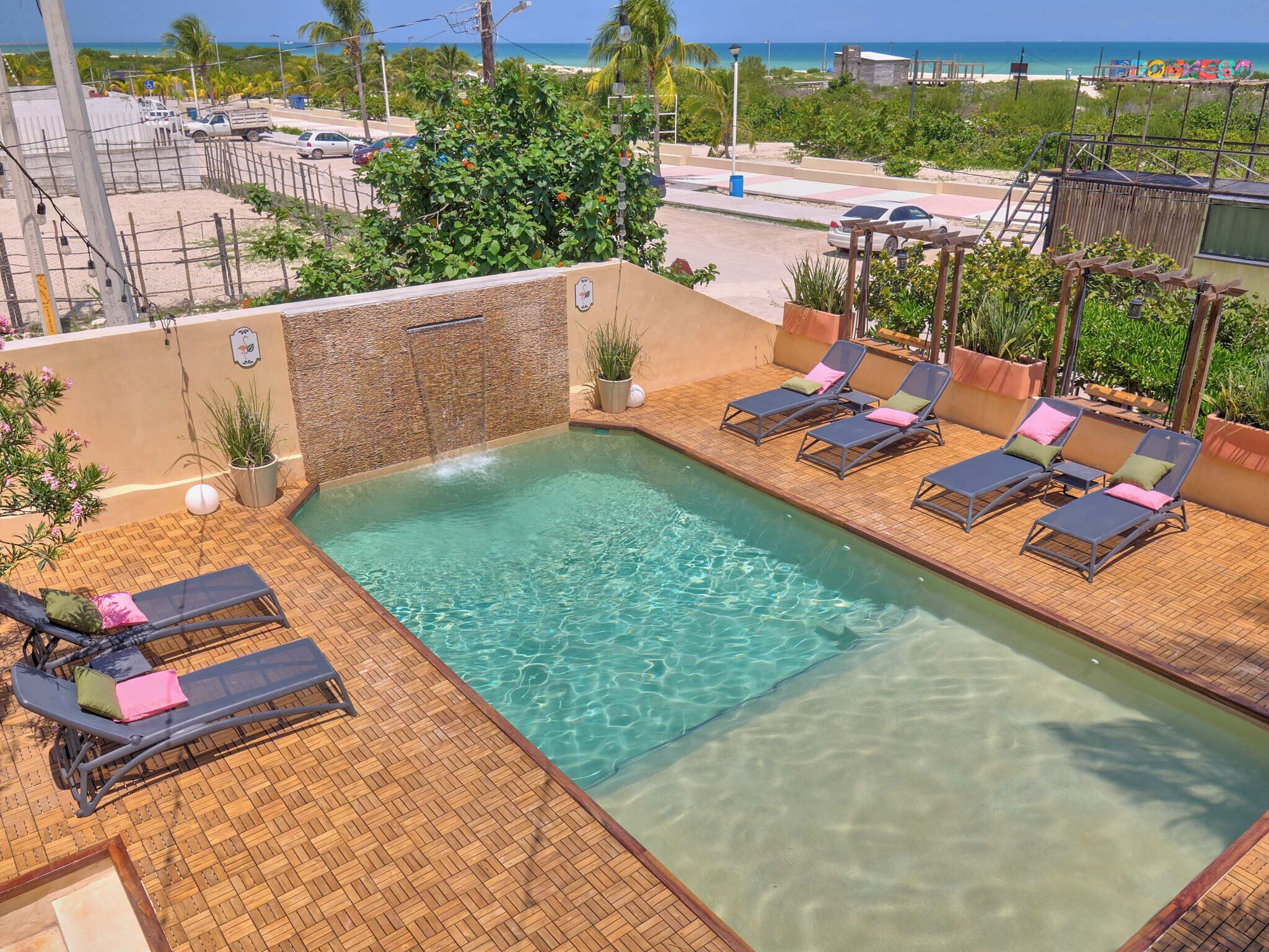 A rooftop pool with lounge chairs and a stone wall.