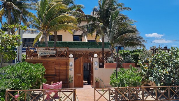 Un edificio de dos pisos con un portón de madera, palmeras y un letrero que dice 'La Boca de la Boca'.