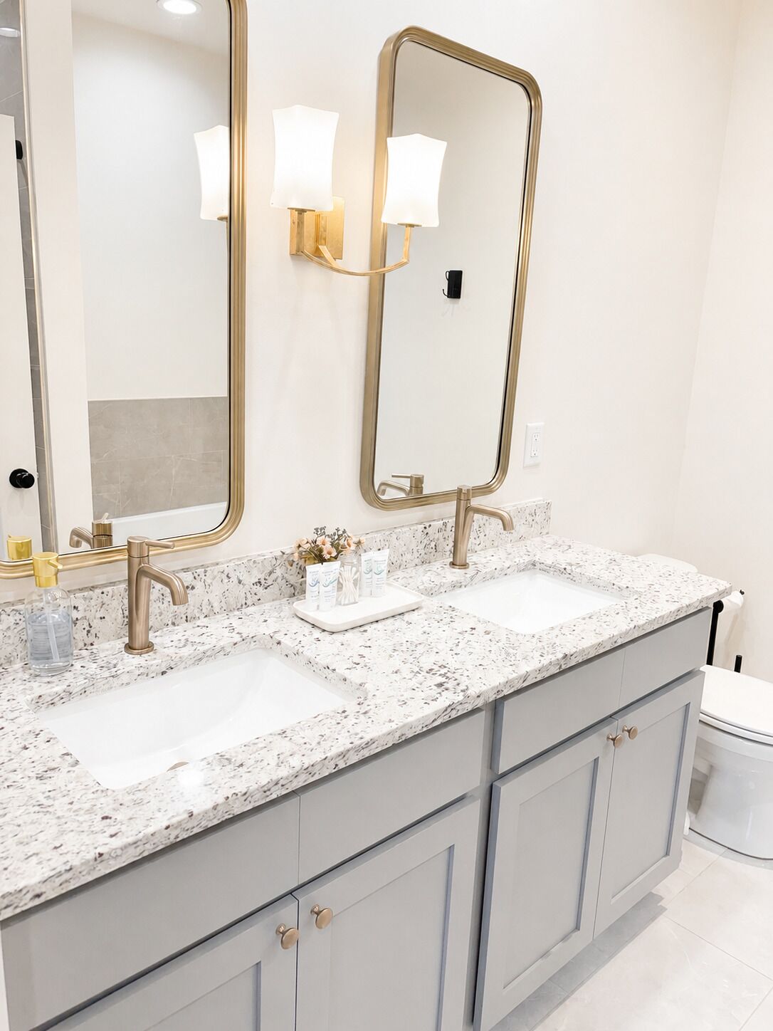 Une salle de bain avec deux lavabos, un grand miroir et des luminaires fixés au mur.