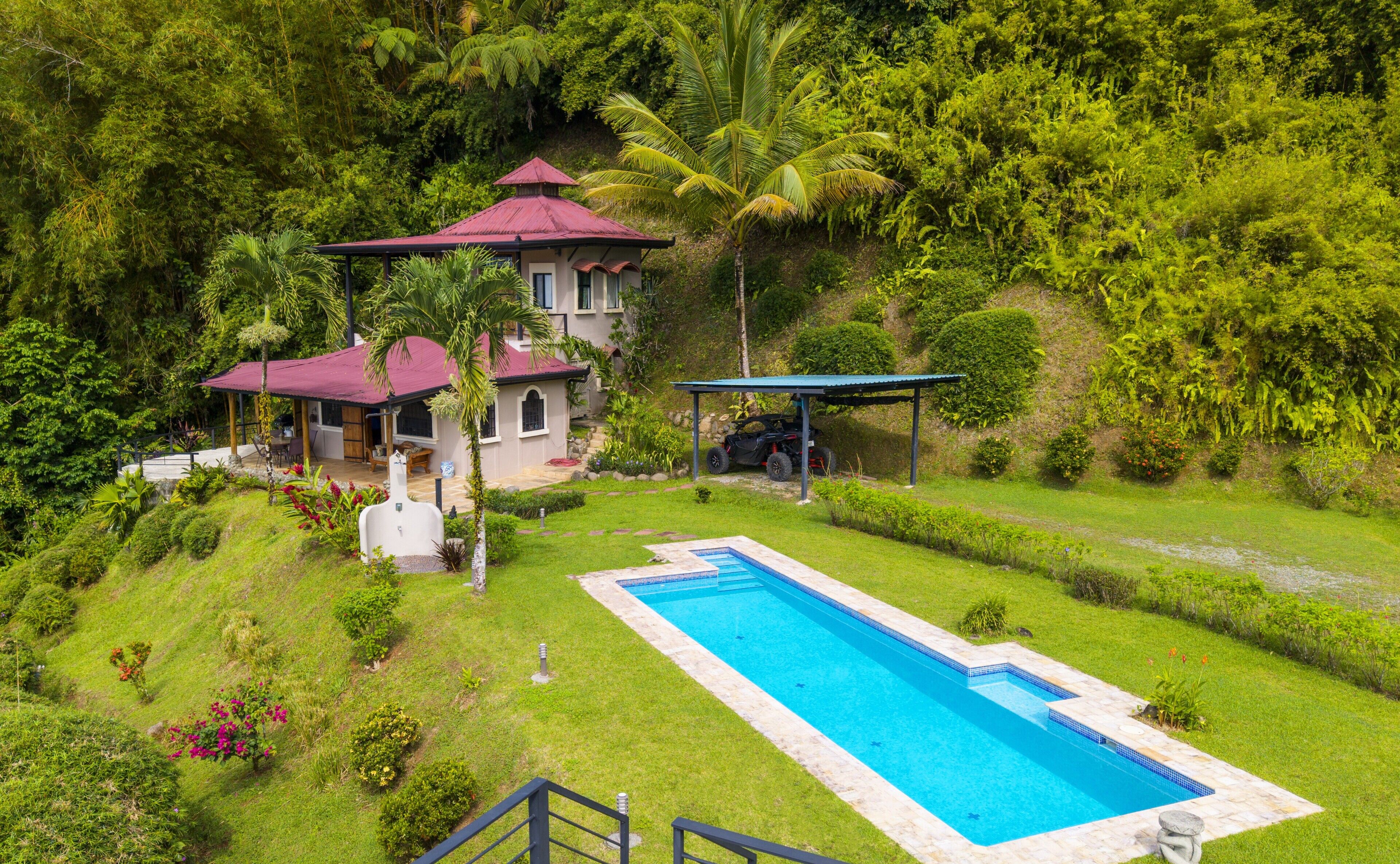 Ein Haus mit Swimmingpool, überdachter Terrasse und üppiger Bepflanzung.