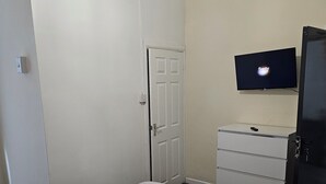 A bedroom with a bed, a dresser, a television, and a door. - M4 Victoria Hub 2 (Newport)