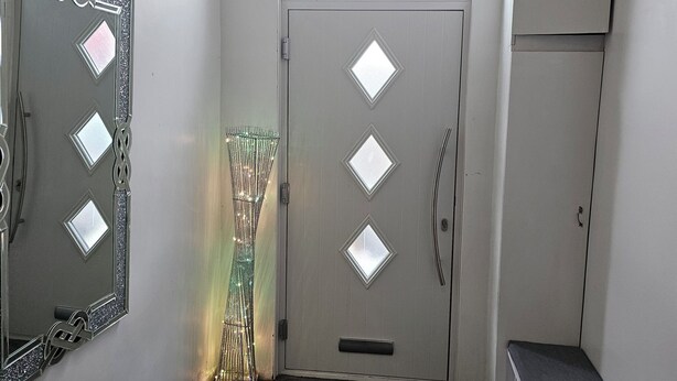 A hallway with a mirrored wall, a door with diamond-shaped windows, a bench, and a cabinet. - M4 Victoria Hub 2 (Newport)