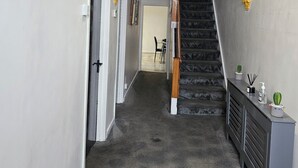 A hallway with a staircase, a chandelier, and a small plant on a console table. - M4 Victoria Hub 2 (Newport)