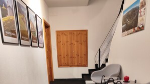 A hallway with a wooden door, a staircase, and framed pictures on the wall. - B&B Berninapass (Poschiavo)