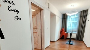 A hallway with a wooden floor, a white wall with a 'Smile Every Day' sign, a black chair, and a table with a laptop. - B&B Berninapass (Poschiavo)