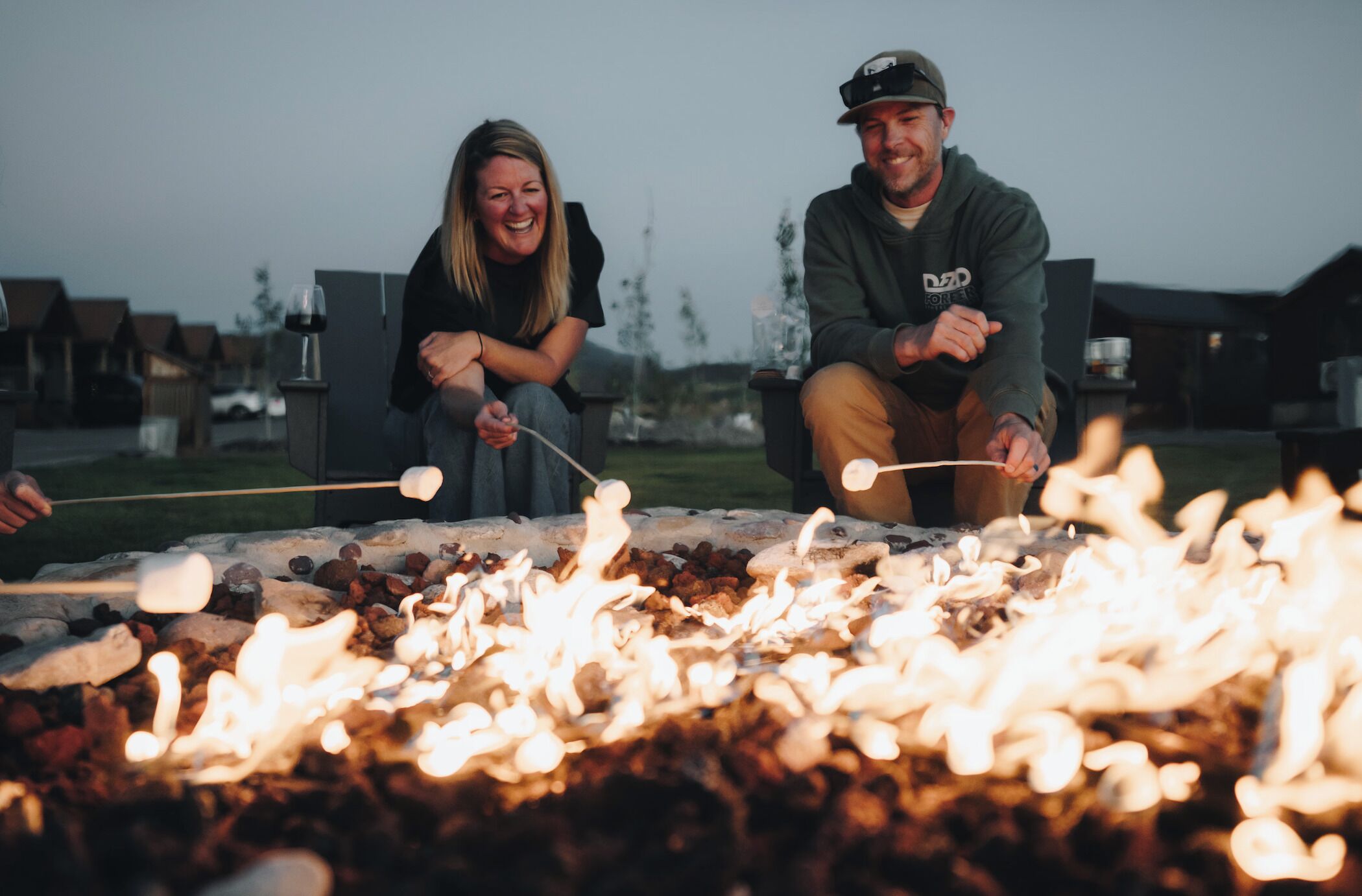 Deux personnes sont en train de faire griller des guimauves au-dessus d’un feu de camp.