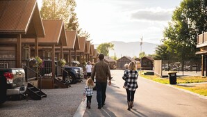 A family walking down a street lined with wooden buildings, some with balconies and flower pots. - Teton Valley RV Resort (Victor)