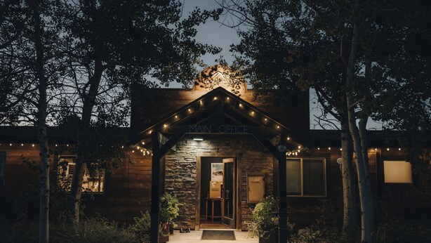 A stone building with a wooden facade, a porch with string lights, and a 'Main Office' sign. - Teton Valley RV Resort (Victor)
