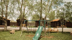 A playground with a slide, swings, and benches. - Teton Valley RV Resort (Victor)