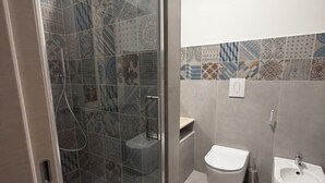Un baño moderno con cabina de ducha de vidrio, inodoro y bidé.
