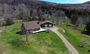Une propriété située en zone rurale, comprenant une grande maison, un garage et une allée non pavée.