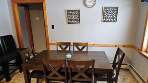 Ein Esszimmer mit Holztisch, Stühlen, einer Uhr und dekorativen Wandverkleidungen.