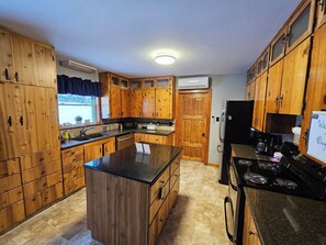 Une cuisine avec des meubles de rangement en bois, un îlot central, une cuisinière et un réfrigérateur.