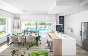 A modern kitchen with a central island, a dining area with chairs, a pool view, and a chalkboard with writing. - Pet friendly home in Galizana (Galizana)