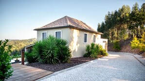 A house with a tiled roof, a paved driveway, and a landscaped garden with various plants. - Golden View (Alvaiázere)