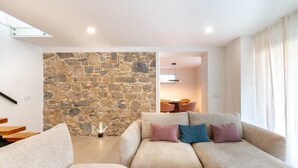 A living room with a stone wall, a sofa set, and a dining area in the background. - Golden View (Alvaiázere)