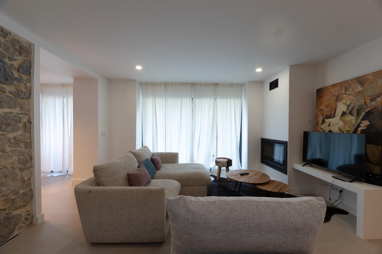 Ein modernes Wohnzimmer mit einer Sofagarnitur, einem Couchtisch, einem Fernseher und einem Gemälde an der Wand.