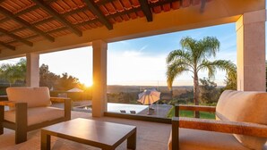 A covered outdoor seating area with a view of a pool and landscape. - Golden View (Alvaiázere)