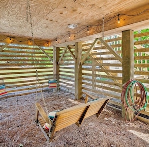 A wooden interior with a swing, a bench, and a hanging light fixture.